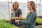 two girls watering plants in the greenhouse