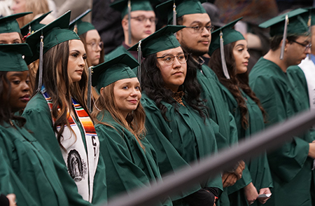 Graduates stand at commencement